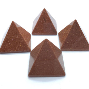 Four sparkling red goldstone pyramids with coppery flecks on white background