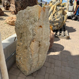 Amber Ice Onyx fountain's crystal-pocked cream face in the outdoor gallery yard beside carved stone sculptures