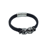 Rare Earth Gallery black braided leather bracelet featuring two stainless steel skull sliders and a magnetic lock.