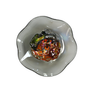 Smoke gray glass wall plate with wavy rim and an amber, green and copper iridescent jewel center