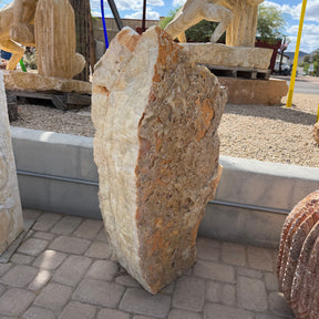 Amber Ice Onyx fountain slab standing on pavers, cream polished face beside rough tan natural rind, no basin