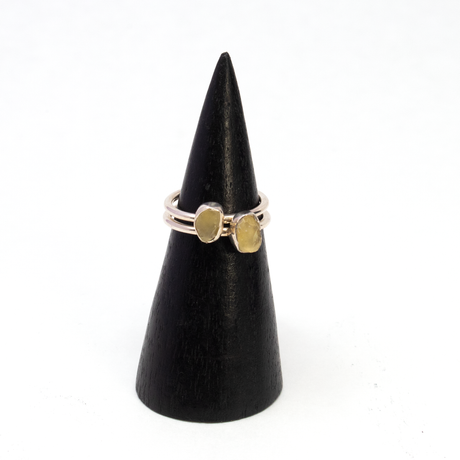 Two Egyptian tektite rings with rough freeform stones in silver bezels shown side by side