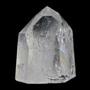 Polished clear quartz point with faceted tip and internal veils, front view on black background