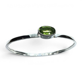 Rare Earth Gallery faceted peridot bracelet featuring an east-west set oval gemstone in a tall silver bezel setting.