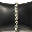 Narrow silver-tone magnetic bracelet with alternating hearts and crossing X links on a display cushion