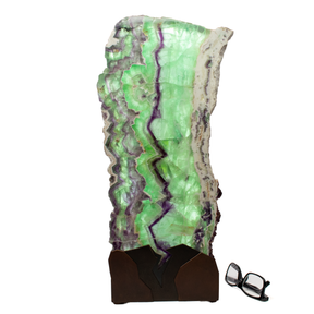 Rainbow fluorite table lamp with a vertical slice design and natural live edge, featuring green and purple hues.