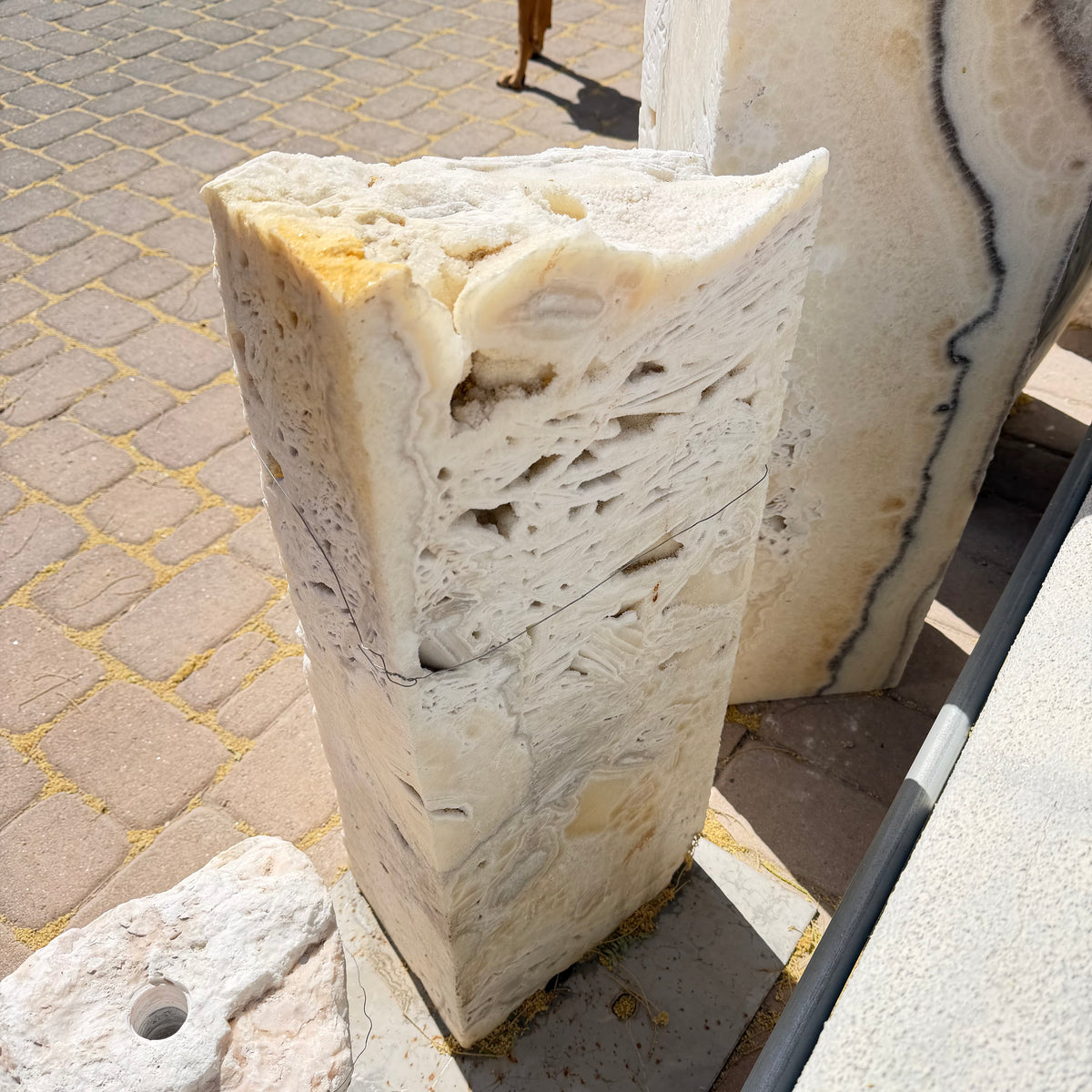 Angled view of the fossil onyx column revealing banded crystal layers beside a black-banded onyx slab