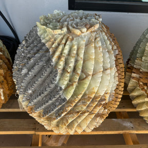 Green Talan barrel cactus sculpture with gray caliche area, dark sparkling patch beside cream and green carved ribs