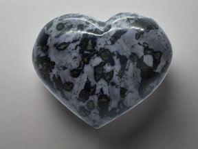 Indigo gabbro heart with a glossy finish, showcasing dark gray and black patterns, displayed on a light background.