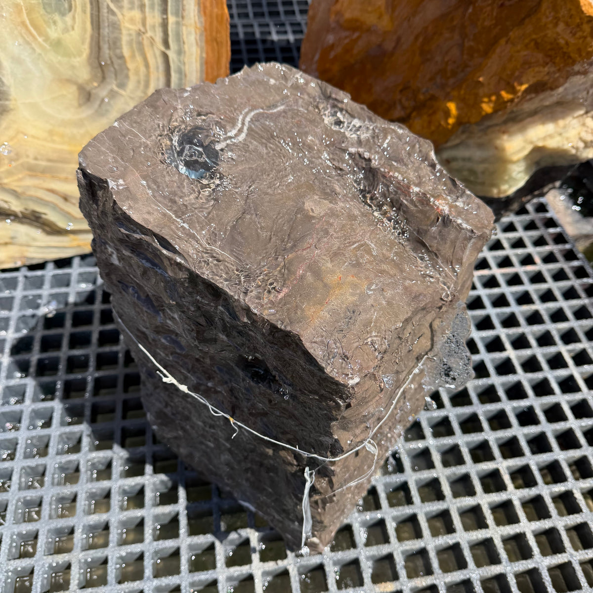 Overhead angle on the wet chiseled top of a black marble block fountain, no basin included