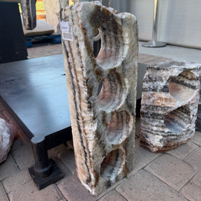 Upright rustic onyx wine rack with four scooped bottle holes down the face, rust and blush banding