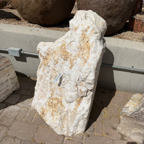 Sunset fossil onyx fountain stone standing upright on pavers with a cream and tan natural rough face