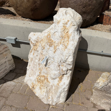 Sunset fossil onyx fountain stone standing upright on pavers with a cream and tan natural rough face