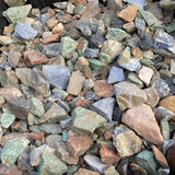Rough Brazilian minerals heaped in a crate, green aventurine, blue sodalite, rose quartz and jasper