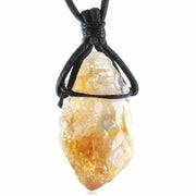 Raw citrine point wrapped in black cord necklace, close-up on white background