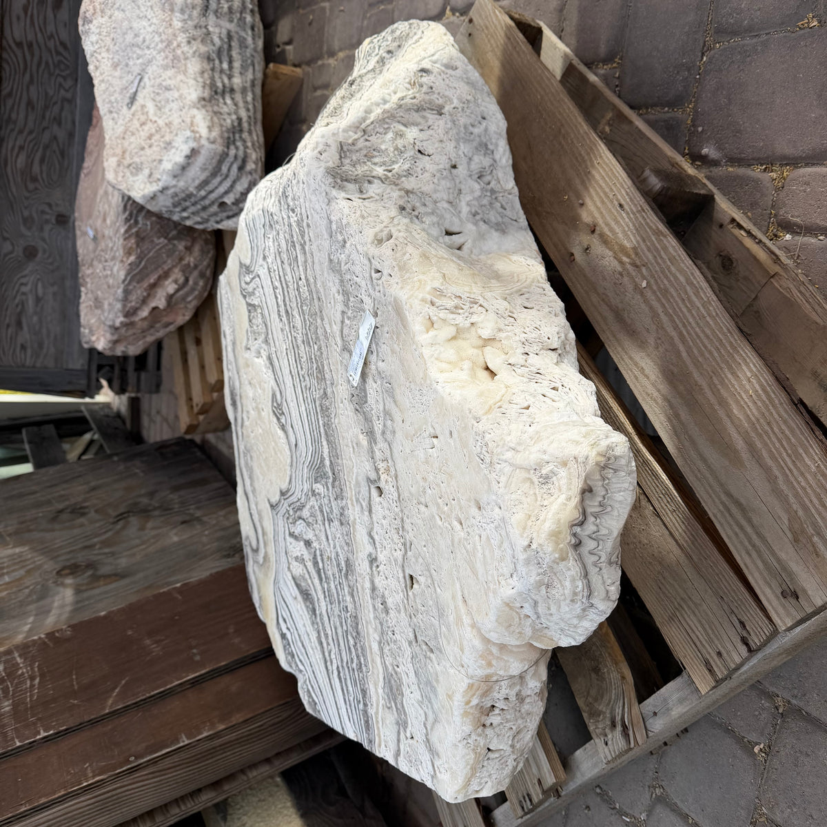 Zebra onyx fountain stone propped at an angle on a pallet, showing its thick rough edge and striped side