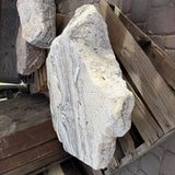 Zebra onyx fountain stone propped at an angle on a pallet, showing its thick rough edge and striped side