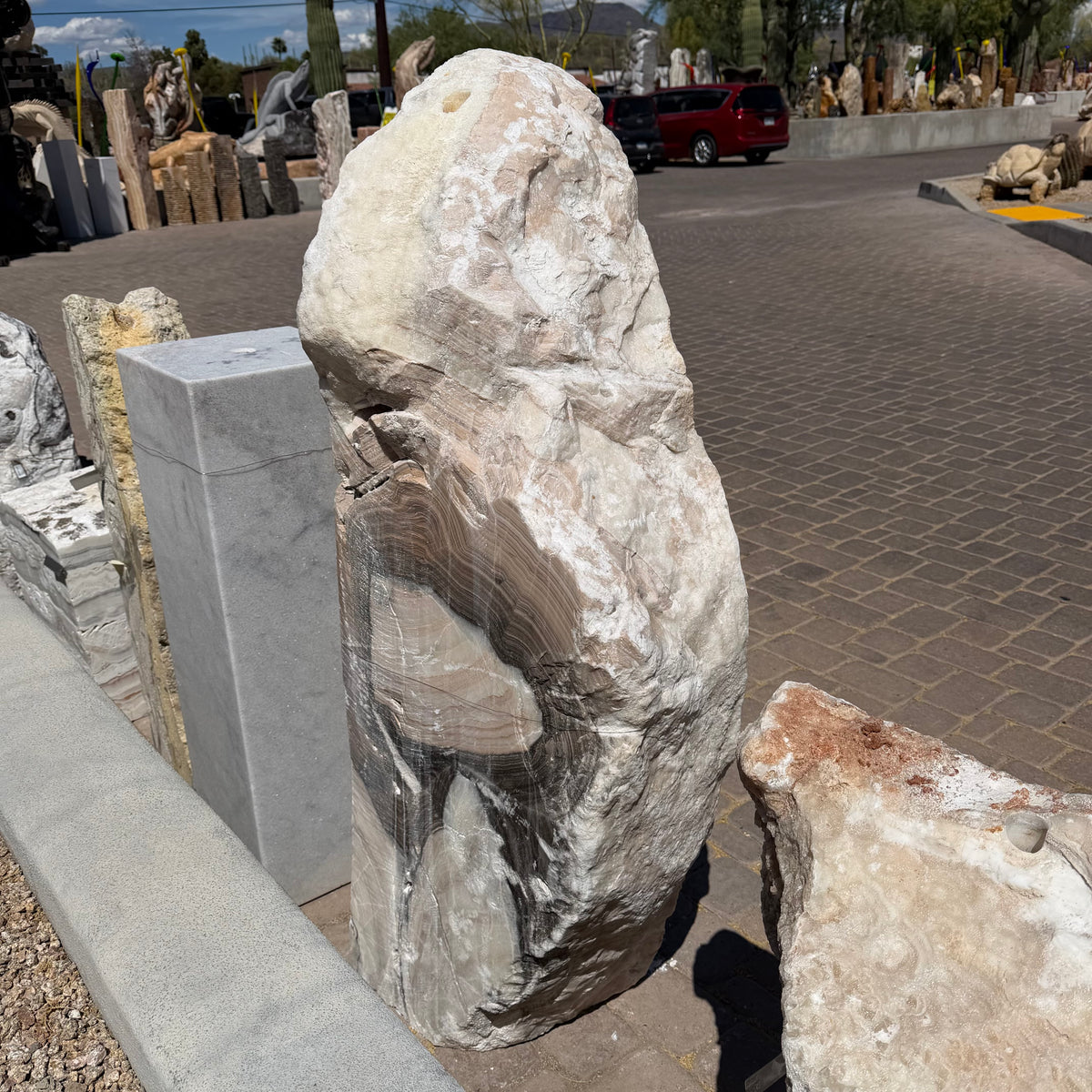 Cosmic Sunset Fossil Zebra Onyx pillar fountain seen from its rough natural face in the outdoor stone yard