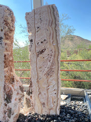 Zebra Fossil Onyx Pillar Fountain running water down cream and rust banding above a black river rock basin