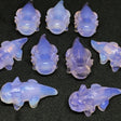 Group of pink opalite axolotl carvings in lavender translucent stone on a black background