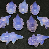 Group of pink opalite axolotl carvings in lavender translucent stone on a black background