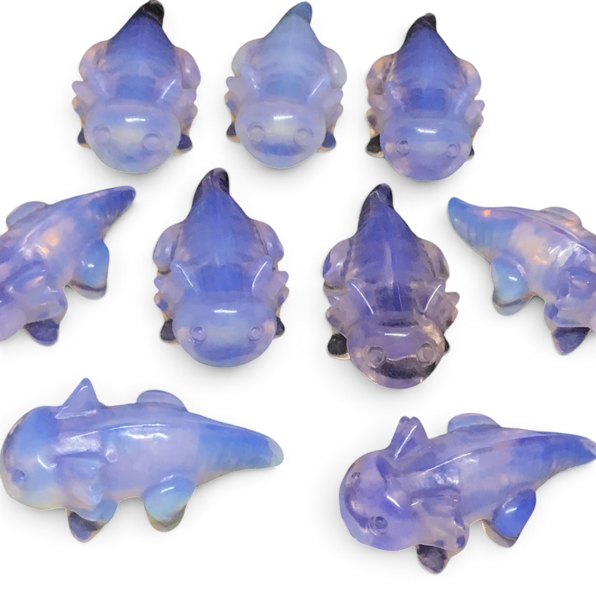 Group of pink opalite axolotl carvings in lavender translucent stone on a black background