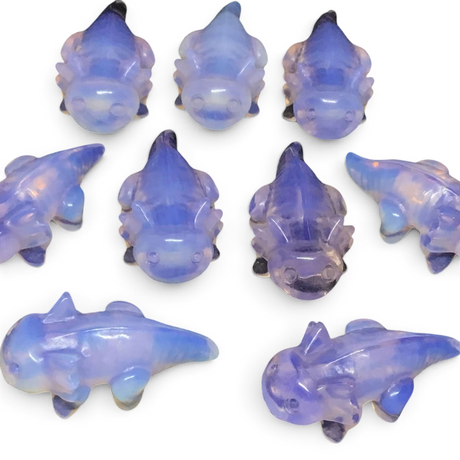 Group of pink opalite axolotl carvings in lavender translucent stone on a black background
