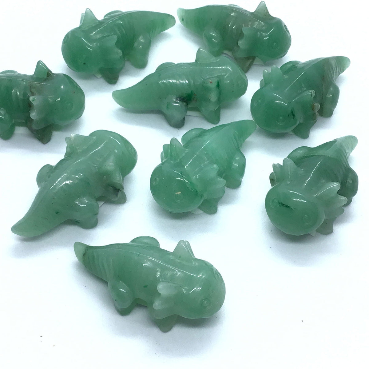 Aventurine axolotl carvings in green stone, several polished figures grouped on white