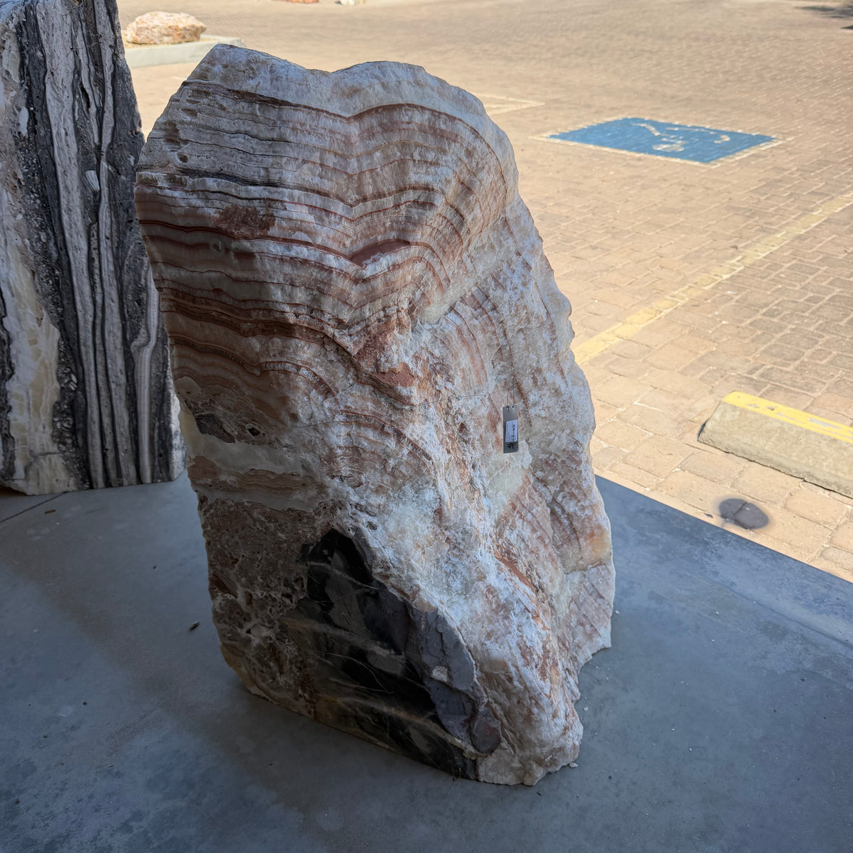 Front face of the Red Sunset onyx and travertine fountain, layered radial bands above a dark inclusion
