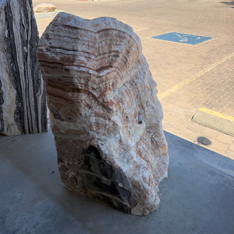 Front face of the Red Sunset onyx and travertine fountain, layered radial bands above a dark inclusion