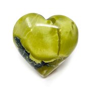 Polished green serpentine heart in lime green with a dark band of pyrite inclusions along one edge