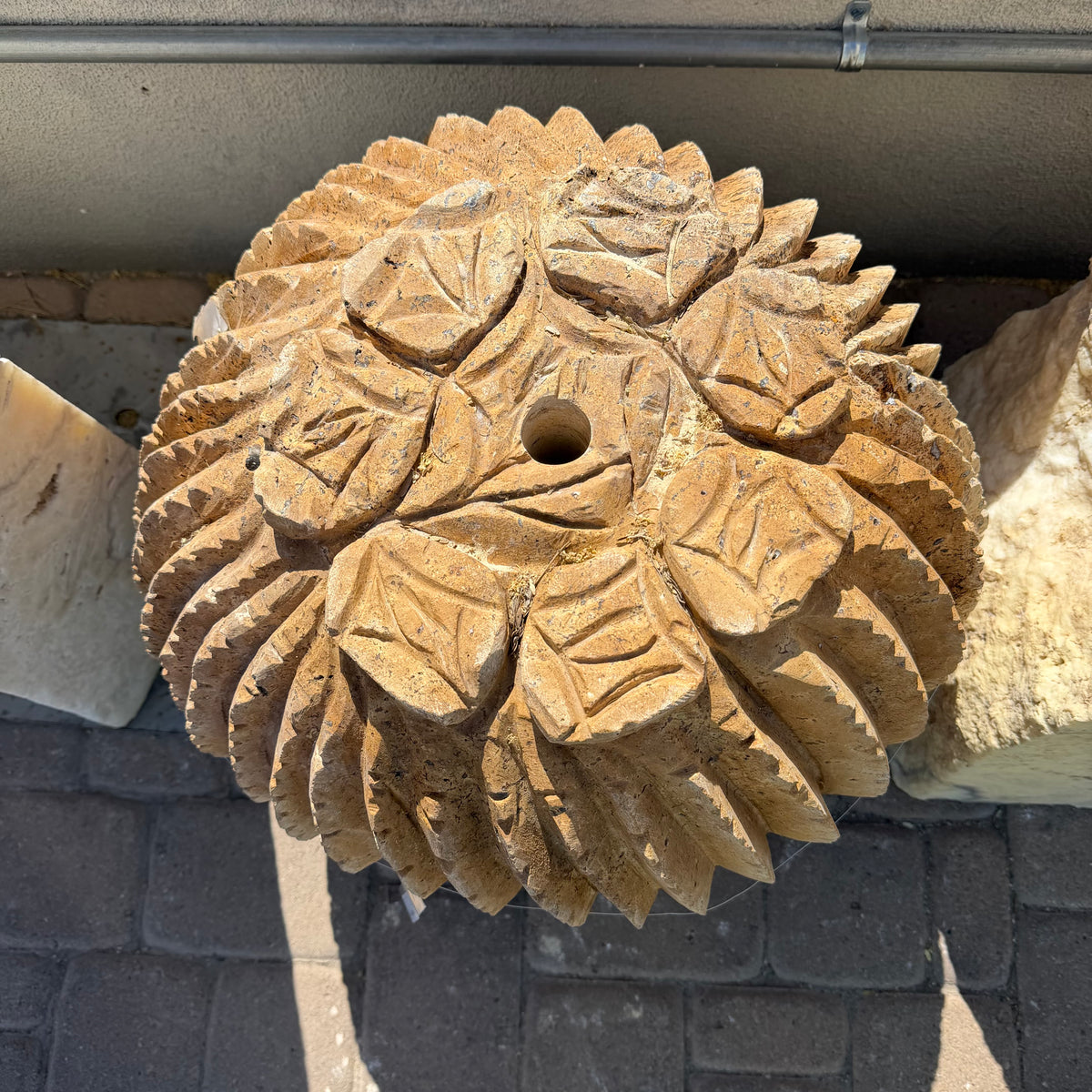 Top-down detail of the sculpted leaf crown and center drill hole on the travertine cactus carving