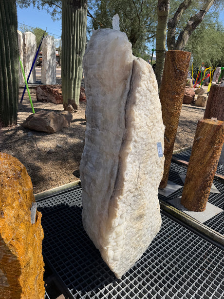 Tall white crystal and gray onyx band fountain beside petrified wood columns in a desert display yard
