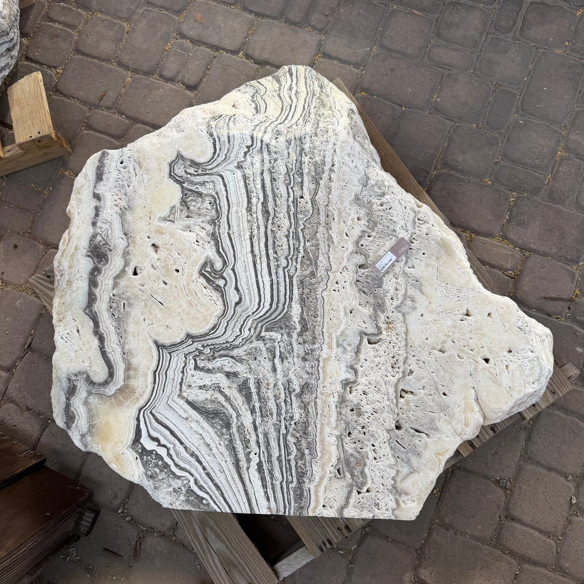 Freeform zebra onyx fountain stone from above, cream surface with charcoal stripes and porous pitted areas