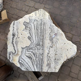 Freeform zebra onyx fountain stone from above, cream surface with charcoal stripes and porous pitted areas