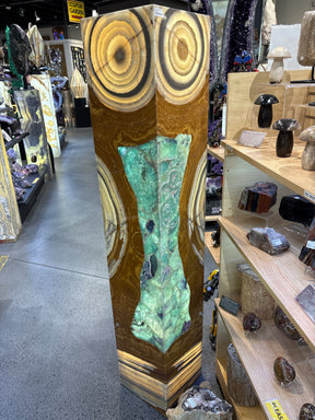 Owl Eyes pedestal luminary with green talan onyx and fluorite inlay, displayed in a stone shop setting.