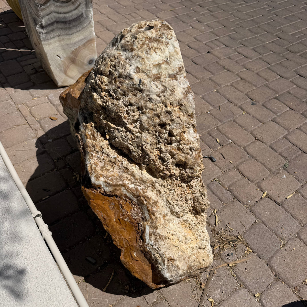 Rough fossil rind exterior and drilled top of the Talan onyx cavern fountain on brick pavers