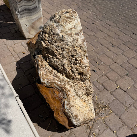 Rough fossil rind exterior and drilled top of the Talan onyx cavern fountain on brick pavers