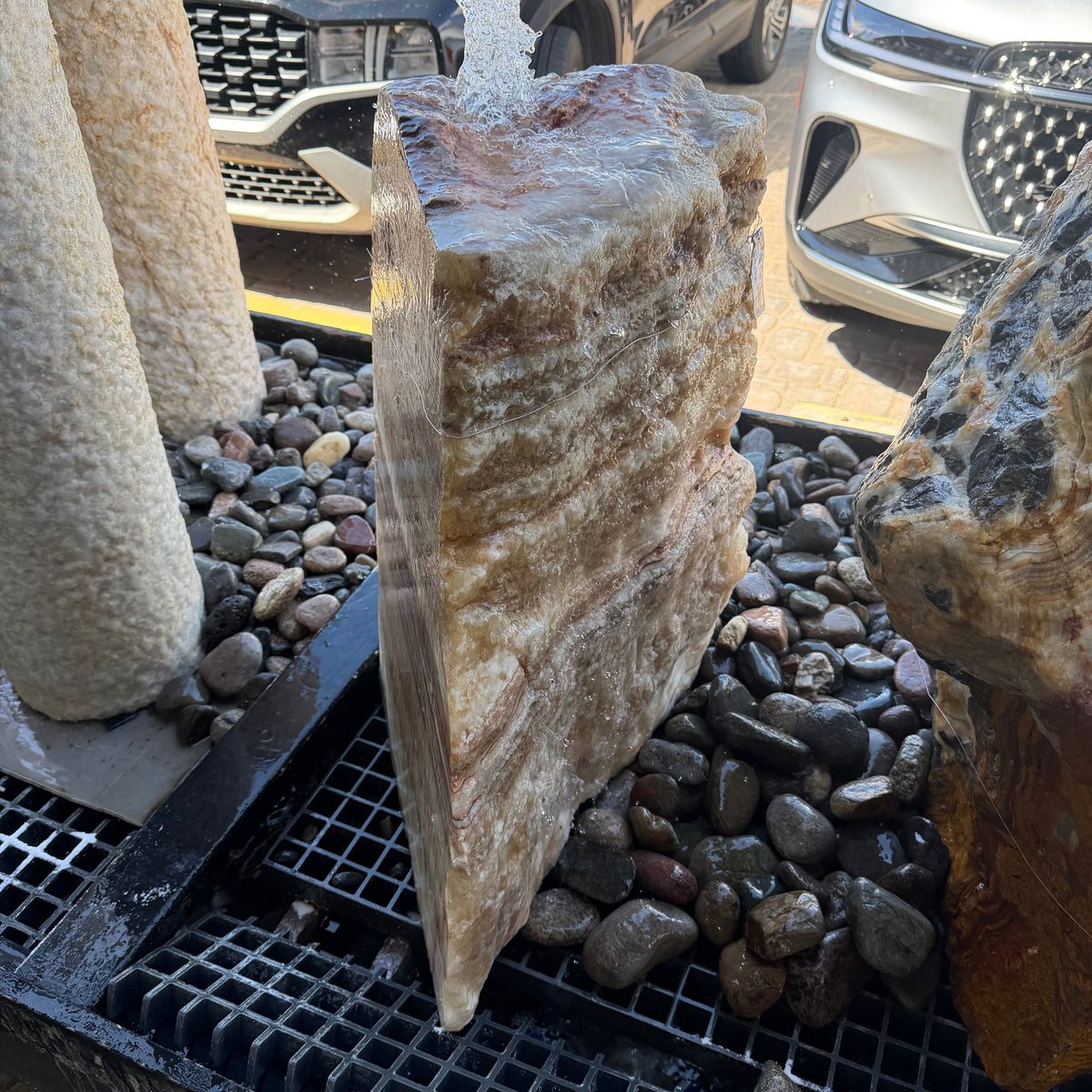 Serpentine onyx boulder fountain from the cut side, sheet of water sliding down the polished face