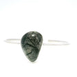 Green-tinged tourmalinated quartz freeform cabochon with black needles, bezel set on a silver bangle cuff