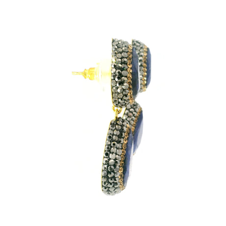 Side profile of blue sapphire two-pear dangle earrings showing gold posts and crystal-set drops