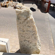 Ice onyx and caliche vertical fountain seen close up, bumpy white druze crystal face above a paver courtyard
