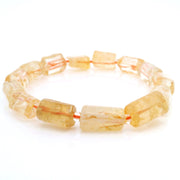 Citrine barrel-bead bracelet strung on orange cord, golden faceted stones, front studio view on white