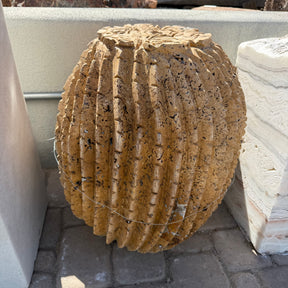 Side view of red travertine barrel cactus fountain showing porous pitted stone and deep flutes
