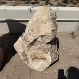 Chocolate travertine onyx boulder fountain photographed head-on against a white wall with price tag
