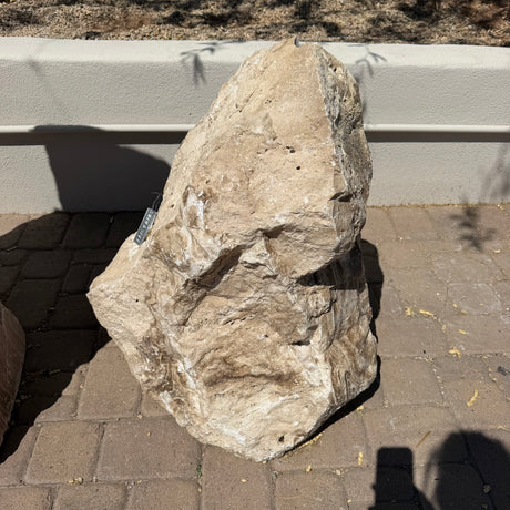 Chocolate travertine onyx boulder fountain photographed head-on against a white wall with price tag
