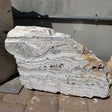 White Zebra boulder fountain standing outdoors, cut face showing wavy white and gray banding