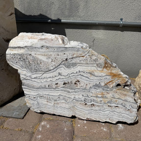White Zebra boulder fountain standing outdoors, cut face showing wavy white and gray banding