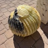 Angled view of the cactus fountain where a black stone wedge cuts through the yellow-green ribs