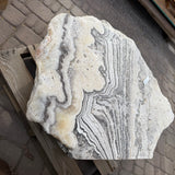 Top face of the freeform zebra onyx fountain stone with swirling gray and white banding on a wooden brace